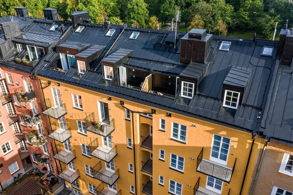 Innergården sedd snett ovanifrån, omgiven av husets orange och gula fasader med balkonger.