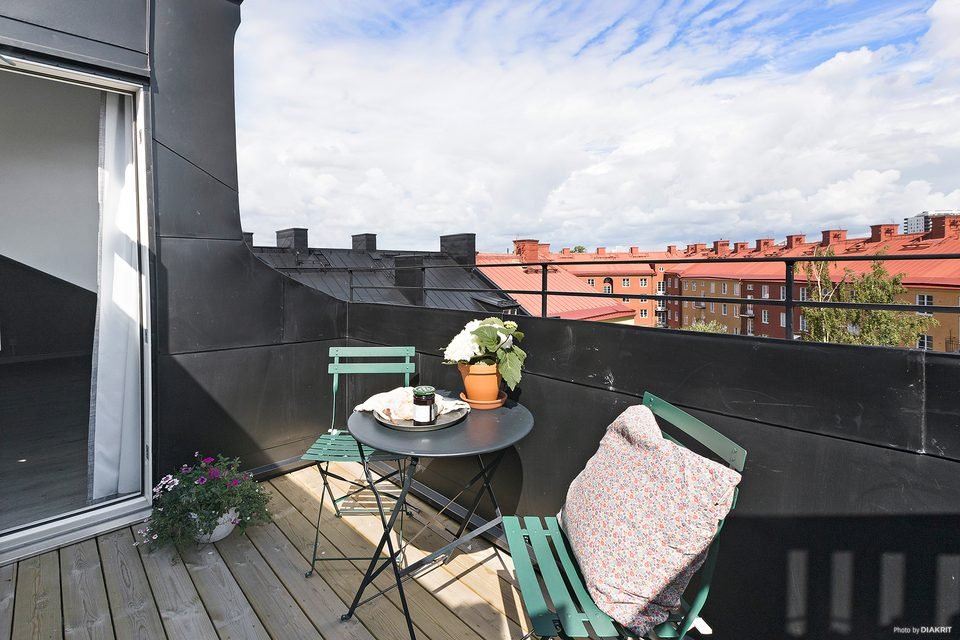 Takterrass med litet bord och två stolar framför lägenhetens glasdörr.