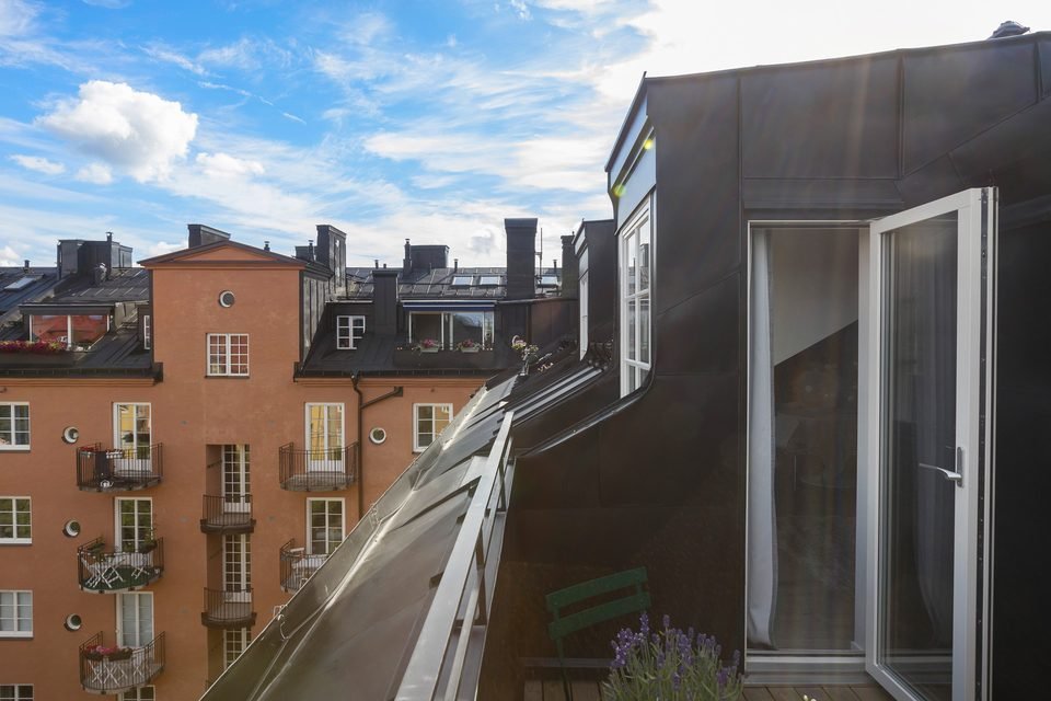 Utsikt från en takterrass över hustak och gata, med terrassdörren i glas till höger.