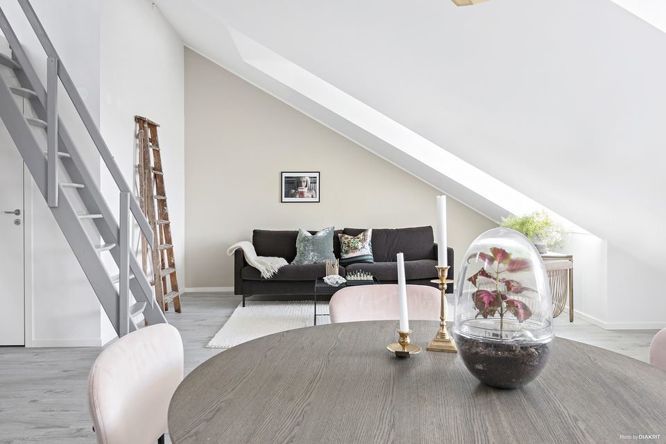 Vardagsrum med soffa och matplats, med trappstege upp till entresolplanet.