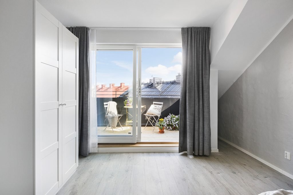 Sovrum i en lägenhet med garderober och glasdörr ut mot en takterrass.